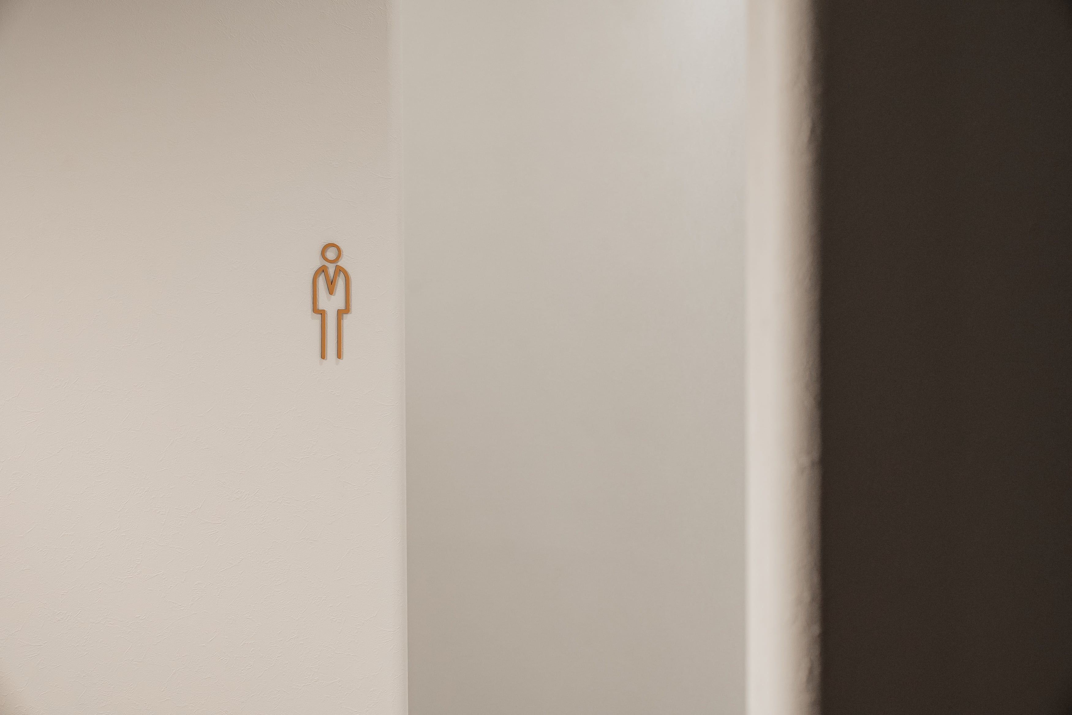 トイレの個室入口デザイン|白壁とアイコンサインの清潔な内装施工例