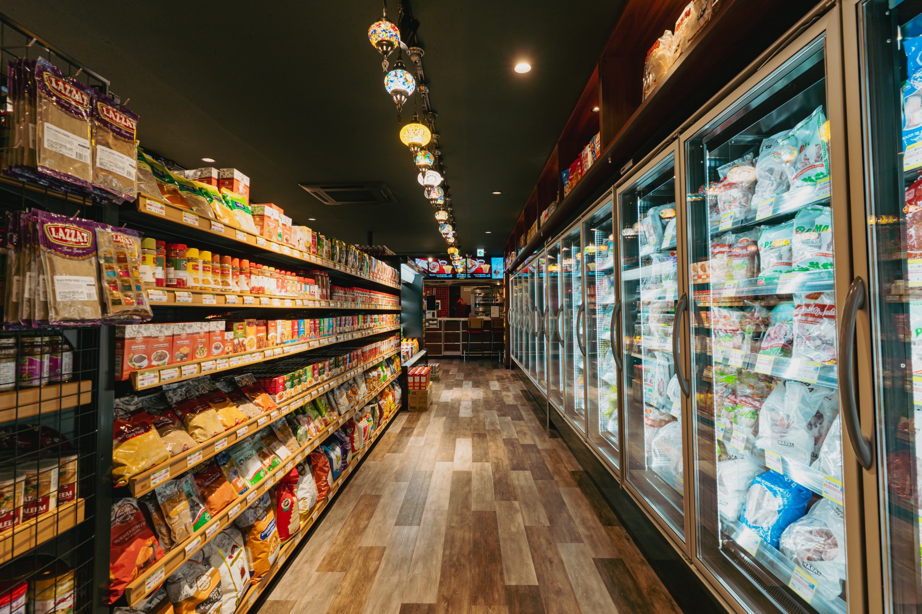 インターナショナルフードマーケット通路の眺め|カラフルなお菓子が並ぶ棚とカウンター方向の視線